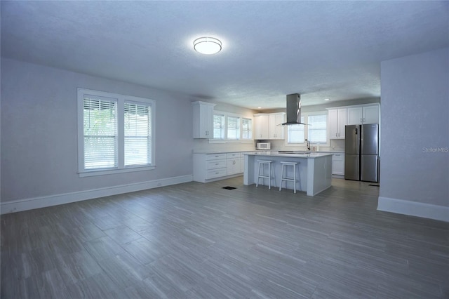 kitchen featuring a kitchen island, freestanding refrigerator, baseboards, and island range hood