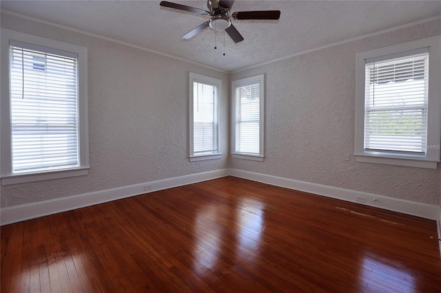 spare room featuring hardwood / wood-style flooring, crown molding, baseboards, and a textured wall