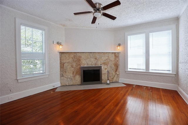 unfurnished living room featuring crown molding, a fireplace, hardwood / wood-style flooring, a textured wall, and a textured ceiling