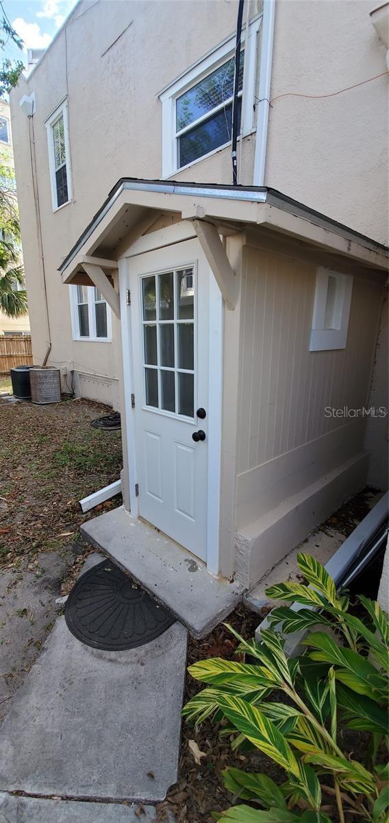 entrance to property with stucco siding and central AC