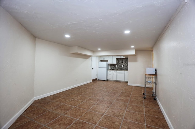 finished basement with dark tile patterned floors, recessed lighting, baseboards, and freestanding refrigerator