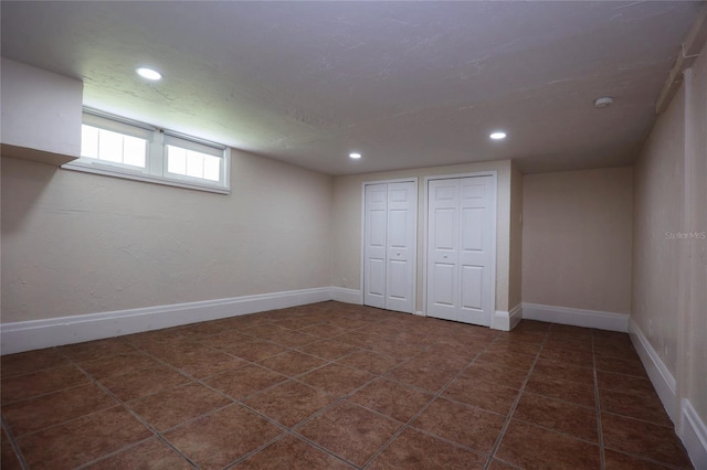 basement featuring recessed lighting, baseboards, a textured ceiling, and dark tile patterned floors