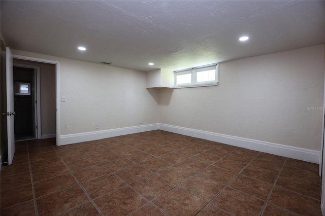 below grade area featuring visible vents, dark tile patterned flooring, recessed lighting, and baseboards