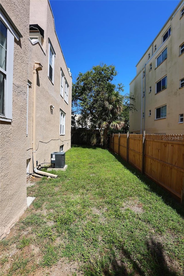 view of yard featuring fence and central AC