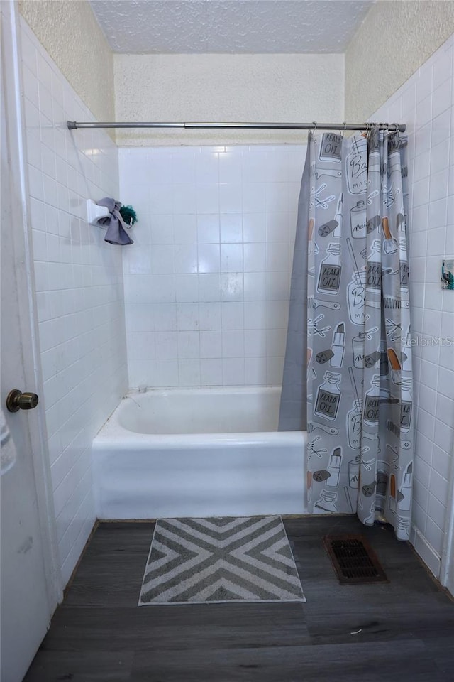 full bath featuring tile walls, shower / bath combo, visible vents, and a textured ceiling