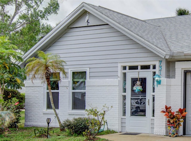 exterior space with roof with shingles and brick siding