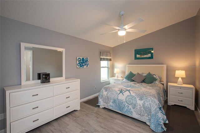 bedroom with a ceiling fan, vaulted ceiling, baseboards, and wood finished floors