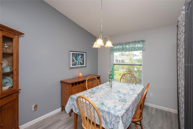 dining space featuring lofted ceiling, light wood-type flooring, baseboards, and an inviting chandelier