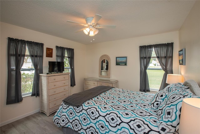 bedroom featuring a textured ceiling, multiple windows, and wood finished floors