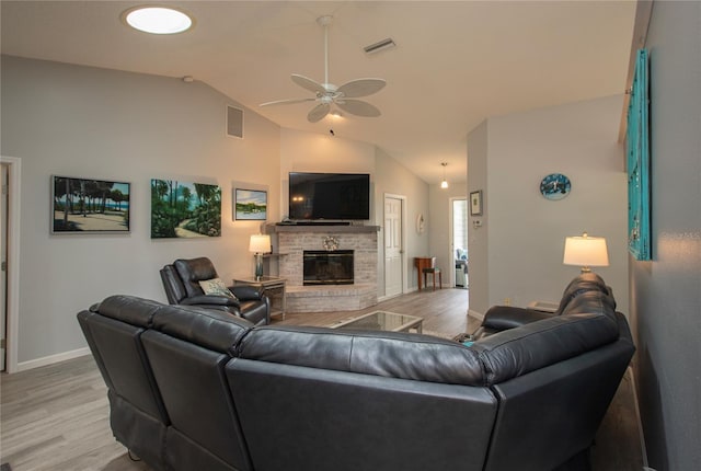 living area with a glass covered fireplace, visible vents, and light wood-style flooring