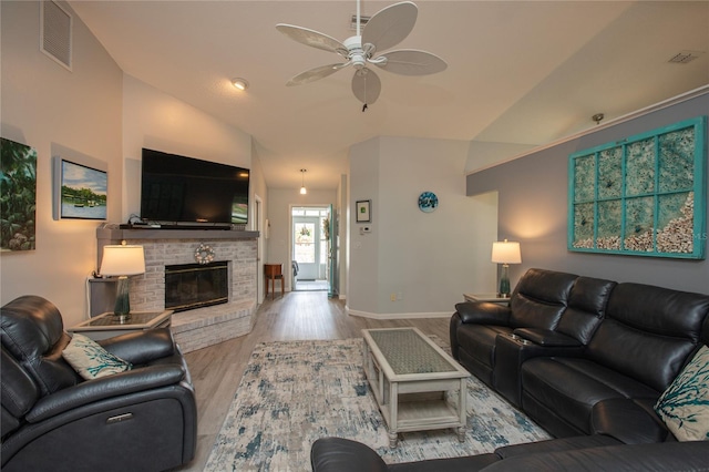 living room featuring lofted ceiling, a fireplace, wood finished floors, visible vents, and a ceiling fan