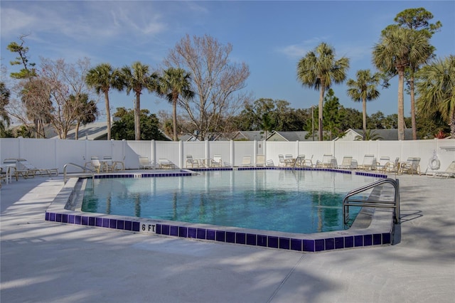 community pool with a fenced backyard and a patio