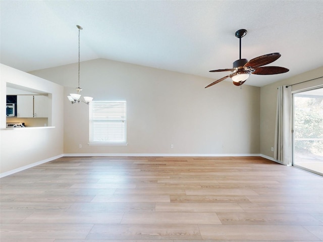 empty room with light wood-type flooring, ceiling fan with notable chandelier, baseboards, and lofted ceiling