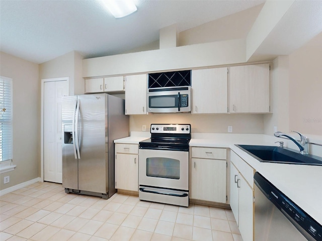 kitchen with stainless steel appliances, light tile patterned flooring, a sink, and light countertops