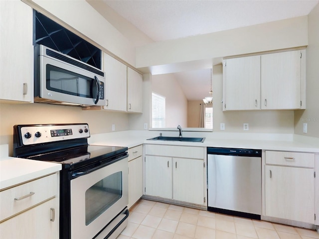 kitchen featuring vaulted ceiling, appliances with stainless steel finishes, light countertops, and a sink