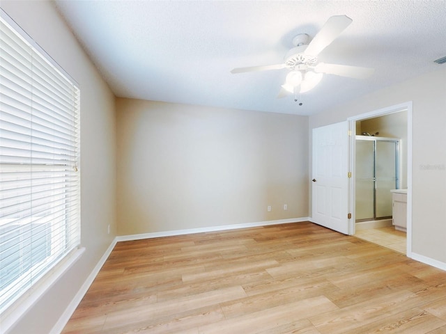 spare room featuring light wood finished floors, visible vents, baseboards, ceiling fan, and a textured ceiling