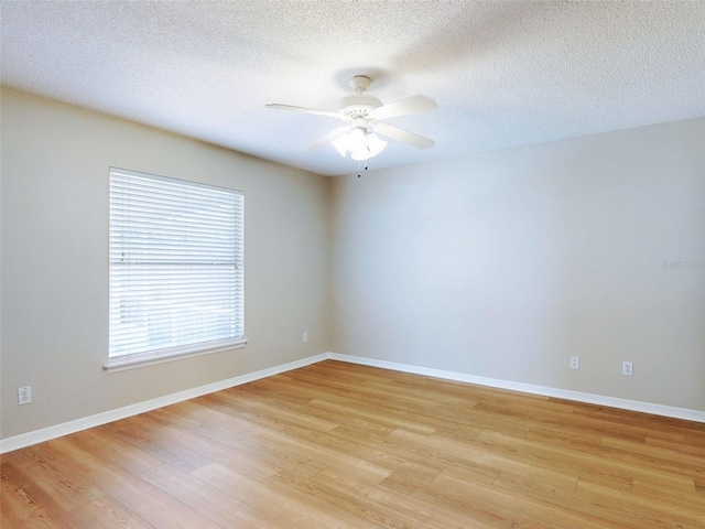 unfurnished room featuring light wood finished floors, ceiling fan, baseboards, and a textured ceiling