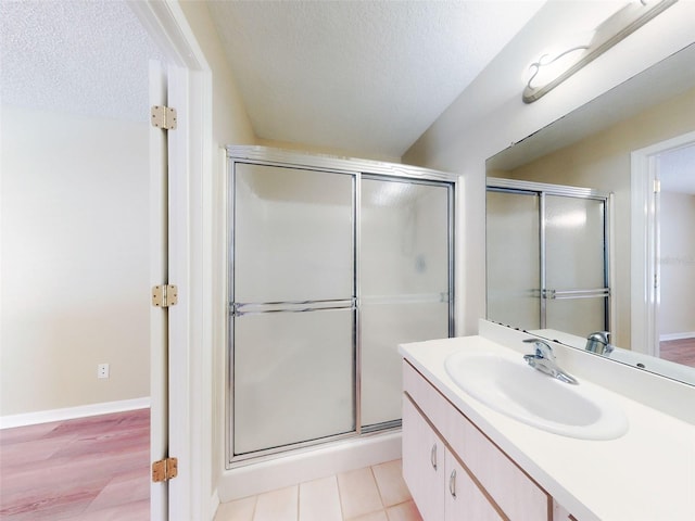 bathroom with a shower stall, baseboards, a textured ceiling, and vanity