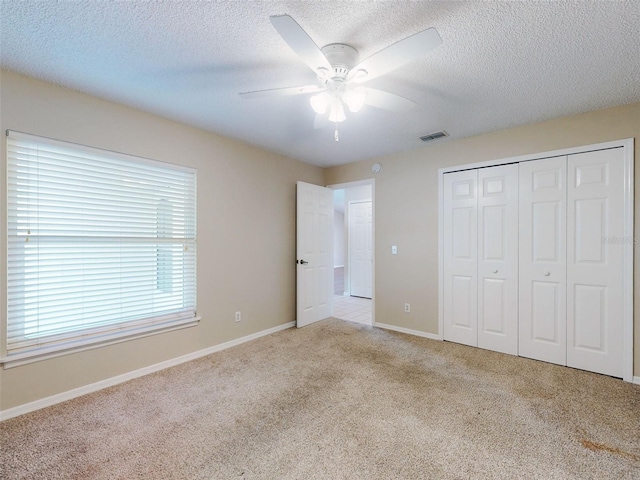 unfurnished bedroom with a closet, visible vents, a ceiling fan, carpet flooring, and a textured ceiling