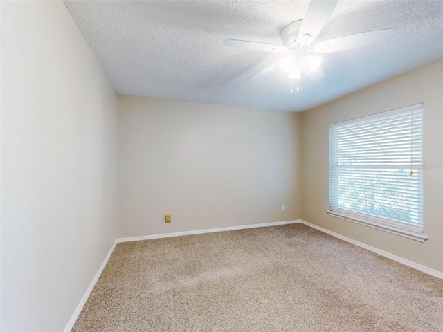 carpeted empty room with ceiling fan, a textured ceiling, and baseboards