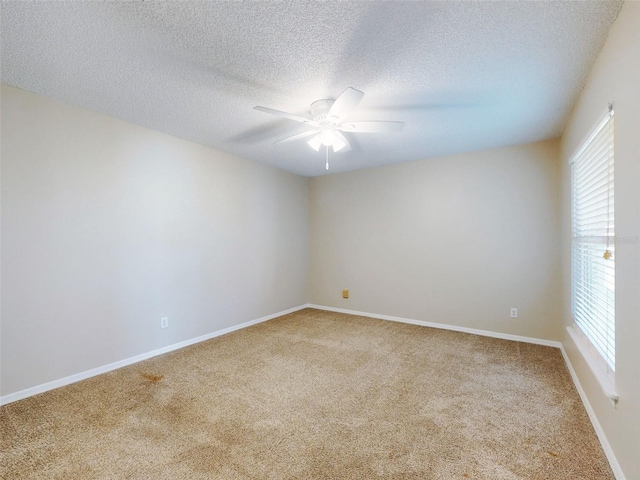empty room with carpet floors, a wealth of natural light, ceiling fan, and baseboards