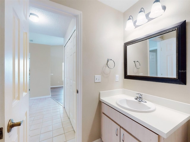 bathroom featuring a textured ceiling, baseboards, vanity, and tile patterned floors