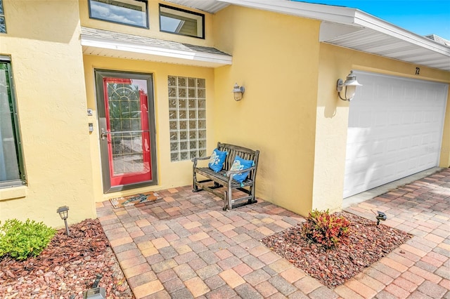 doorway to property featuring an attached garage and stucco siding