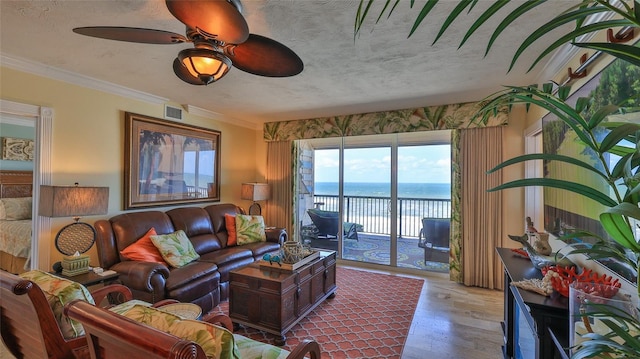 living area with a water view, visible vents, ornamental molding, a textured ceiling, and wood finished floors