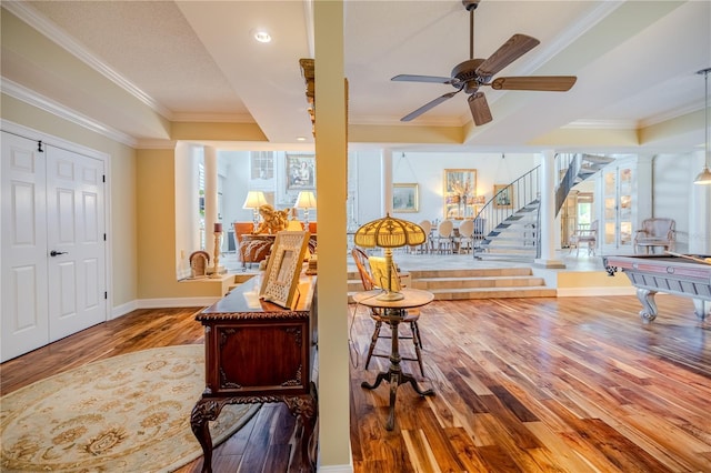 foyer featuring ornamental molding, ceiling fan, wood finished floors, baseboards, and stairs