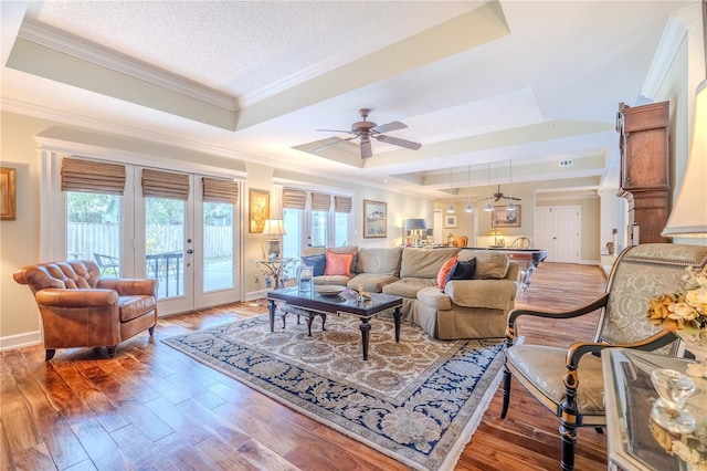 living room featuring a healthy amount of sunlight, light wood finished floors, and a tray ceiling