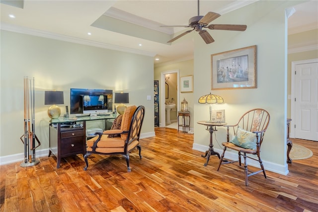 office space with crown molding, baseboards, a raised ceiling, and wood finished floors