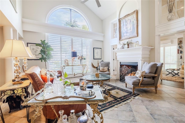 living room with a healthy amount of sunlight, a lit fireplace, high vaulted ceiling, and a ceiling fan