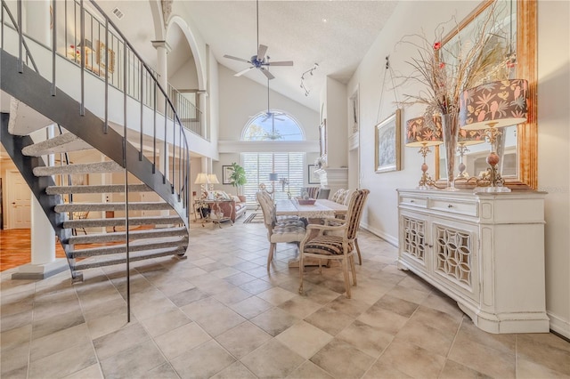 dining room with high vaulted ceiling, ceiling fan, stairway, and baseboards