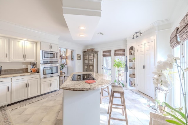 kitchen with light stone countertops, plenty of natural light, stainless steel appliances, and a center island