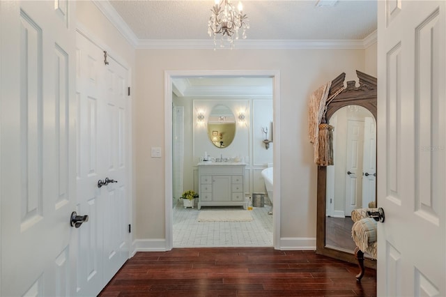 corridor with baseboards, ornamental molding, a chandelier, and wood finished floors