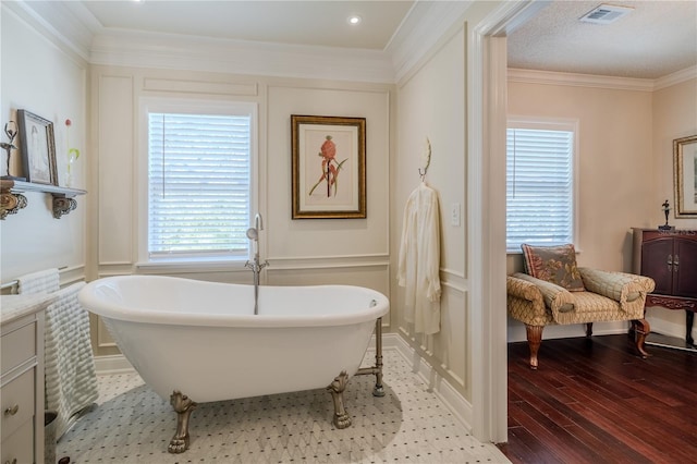 full bathroom with visible vents, a decorative wall, ornamental molding, wood finished floors, and a freestanding tub