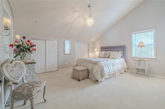 bedroom featuring carpet flooring, vaulted ceiling, a textured ceiling, and two closets