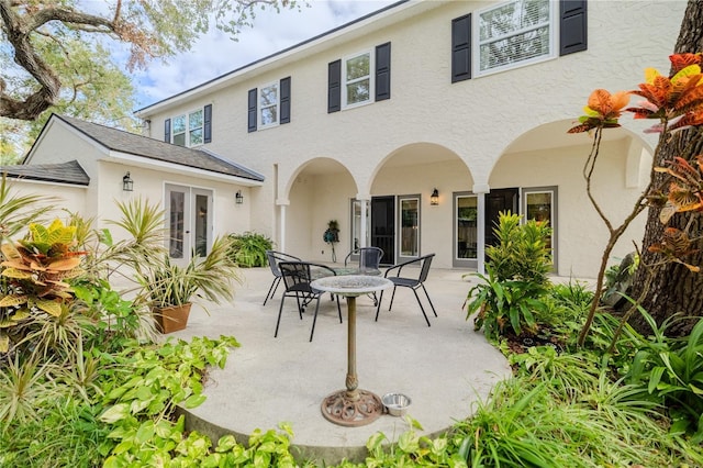 rear view of property featuring french doors, a patio area, and stucco siding