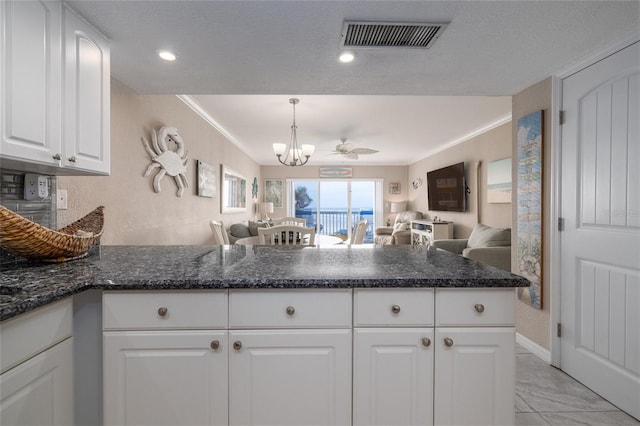 111 N Atlantic Ave Unit A219, New Smyrna Beach, FL 32169 - kitchen featuring crown molding, open floor plan, a peninsula, white cabinetry, and visible vents
