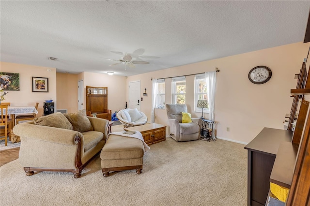 living area with light carpet, baseboards, visible vents, a ceiling fan, and a textured ceiling