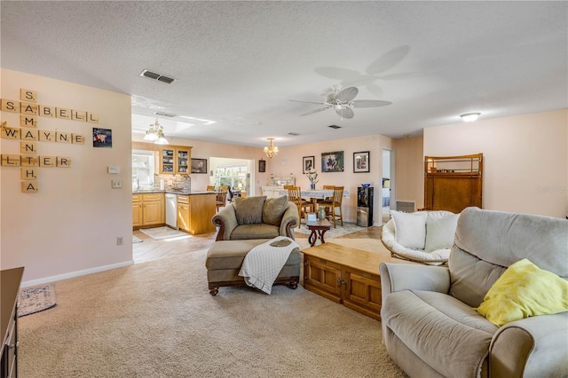 living area with a textured ceiling, light colored carpet, ceiling fan with notable chandelier, visible vents, and baseboards