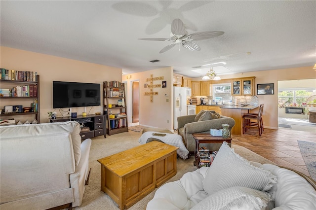 living area featuring ceiling fan, a textured ceiling, and light tile patterned floors