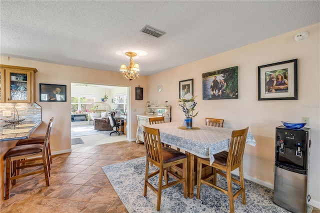 dining area with visible vents, a textured ceiling, baseboards, and an inviting chandelier