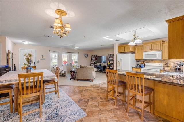 dining room with visible vents, a textured ceiling, and ceiling fan with notable chandelier