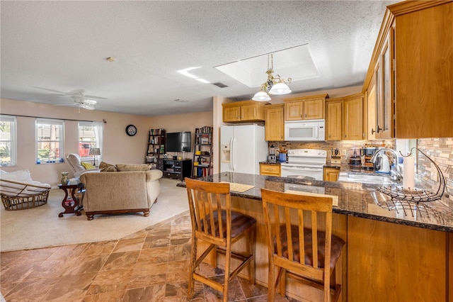 kitchen with white appliances, a sink, open floor plan, tasteful backsplash, and a raised ceiling