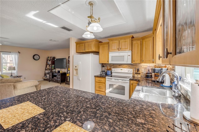 kitchen featuring white appliances, a sink, visible vents, open floor plan, and a raised ceiling