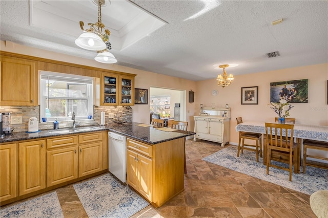 kitchen featuring a tray ceiling, visible vents, a sink, dishwasher, and a peninsula