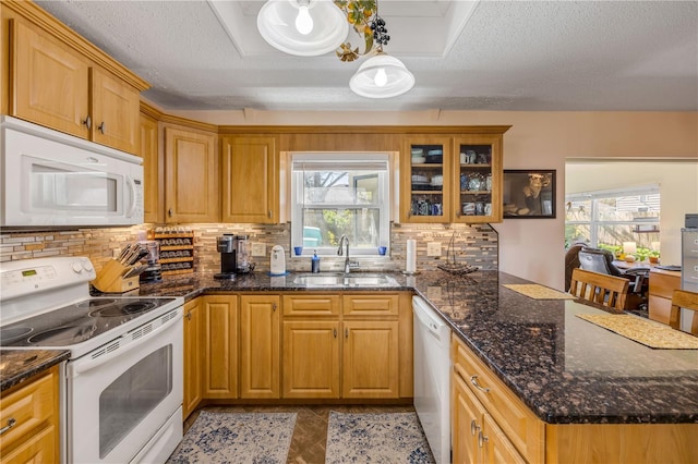 kitchen featuring white appliances, glass insert cabinets, a peninsula, a sink, and backsplash