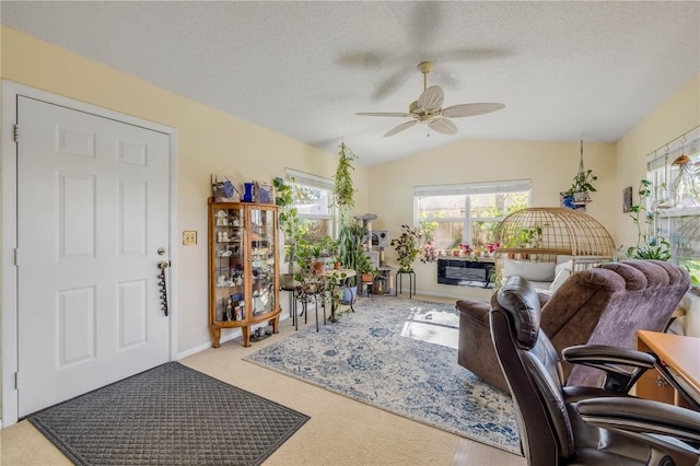 interior space featuring carpet flooring, vaulted ceiling, a textured ceiling, and ceiling fan