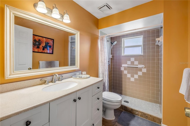 full bath featuring toilet, visible vents, tiled shower, and vanity